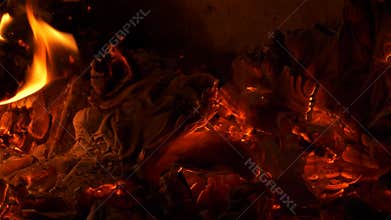 Burning paper ashes in the fireplace, with vibrant glowing, and fire flames.