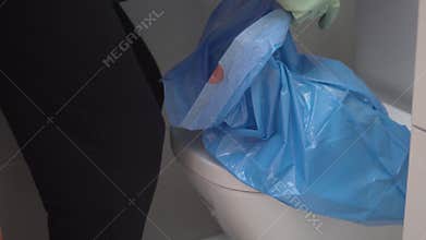 Close-up, man throwing garbage from a bucket in a toilet into a garbage bag