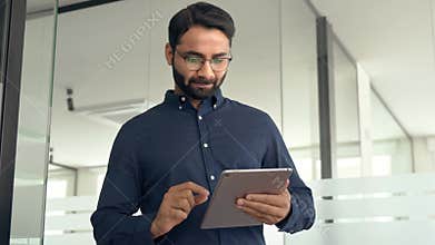 Busy Indian business man project manager using tab walking in office.