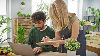 Woman and man collaborate in a flower shop with a laptop, clipboard, and vibrant tulips on the worktable