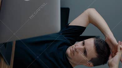 Vertical of Tired man stops typing article stretching hands and neck