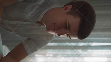 Vertical of Man looks at screen of laptop typing text for new article