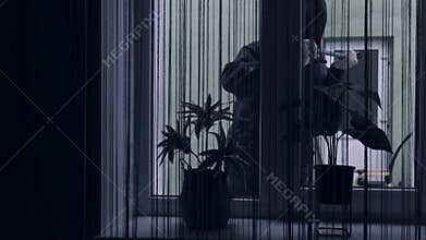 A thief or bandit in a mask breaks open a window with a crowbar and breaks into the house.