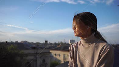 A woman is sitting on a ledge with her phone in her hand. She is looking at the phone and she is in a contemplative mood