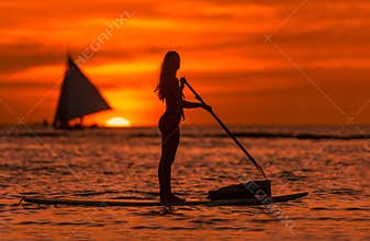 Summer feelings, beautiful woman on paddle board at sunset on the sea