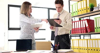 Man and woman compare project plans exchanging clipboards