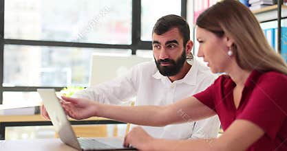Male boss and female manager professionals collaborate on laptop