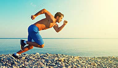 Man athlete running by sea at sunset outdoors