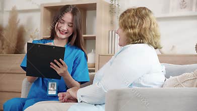 Caregiver sitting on sofa checkup and diagnostic with elderly woman patient about health in living room at home.