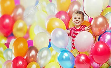 Laughing boy playing among the baloons