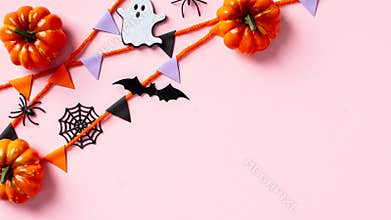 Halloween decor, pumpkins, ghosts, bats and spiders, bunting garland on pink background. Flat lay, top view