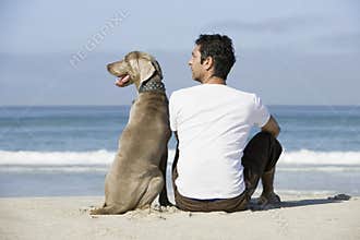 Man And Dog Sitting On Beach