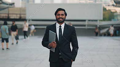 Portrait of Corporate leader with device under arm standing at square