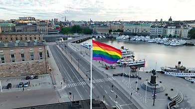 Aerial view at huge LGBTQ flag over Stockholm. Sex minority banner waving in wind sky above town.