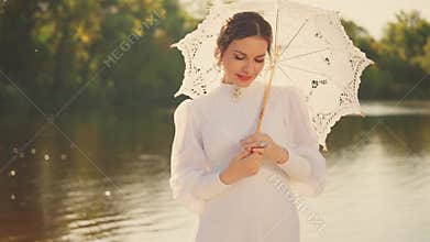 happy woman holding white lace umbrella in hands looking at camera with love, vintage dress old style. Noble girl