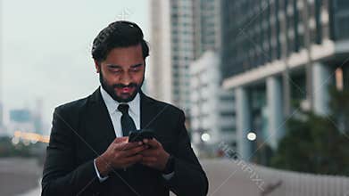 Happy businessman downloading application on gadget after busy day