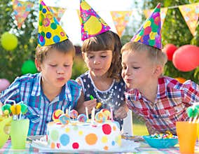 Kids at birthday party blowing candles on cake