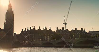 People, traffic and red buses crossing Westminster Bridge at sunset by Big Ben and the Houses of Parliament, London, England