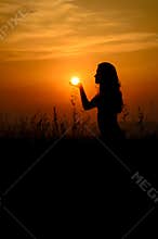 Girl holding the sun in her palm
