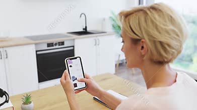 Caucasian woman shopping online using phone in modern kitchen