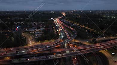 Aerial drone night view of a multi-level highway intersection with moving cars in the city of Rotterdam
