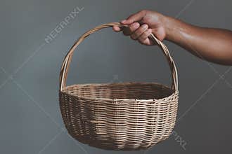 Hand holding empty wooden wicker basket  on white background.