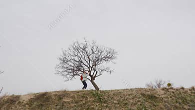 Hiker walking near bare tree on cloudy day