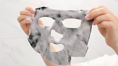 Female hands holding sheet of black bubble mask close-up front view.