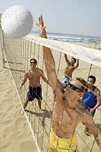 Young Men Playing Volleyball On Beach