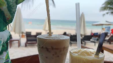 Delicious ice latte coffee Mango smoothie on a seaside in summer. Cold drink at beach cafe outdoors. Travel and enjoy