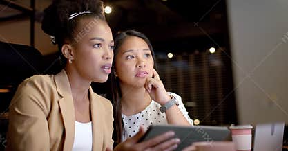 Young African American woman and biracial woman collaborate in a business office