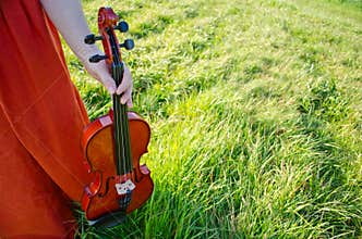 A woman holding a violin in nature horizontal