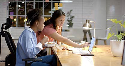 Young African American woman and biracial woman collaborate in a modern business office