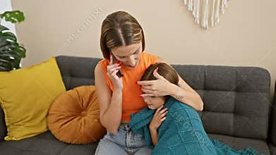 A caring mother comforts her sick daughter while having a phone consultation in their cozy living room