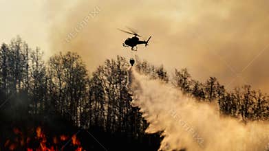 Fire fighting helicopter dropping water on wildfire