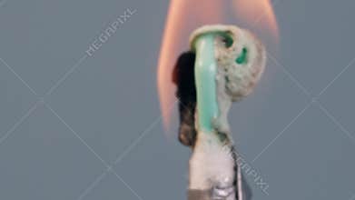 An ear plastic cotton swab, wrapped in silver foil on a wooden stick, isolated on a grey background, burns, melts