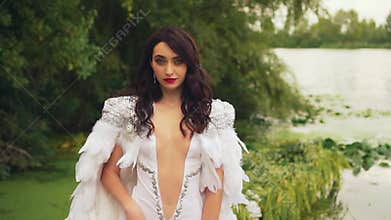 Fantasy woman queen in white dress. Creative clothing, cloak natural feathers