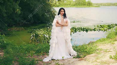 Fashion Fantasy woman queen in long white dress natural feathers. river nymph