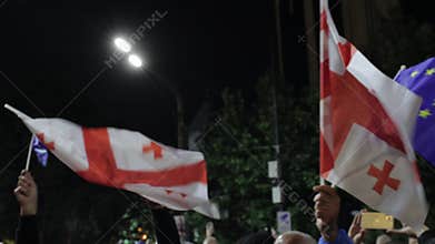 Tbilisi, Georgia - 12th May, 2024: Demonstrators energetically wave Georgian and EU flags during a nighttime protest