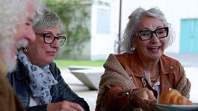 Senior group of retired people having breakfast together at bar terrace.