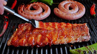 Chef spread sauce pork ribs On Grill. Cooking natural sausage on grill. Slow motion. Close up