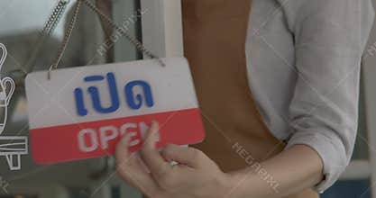 Person in apron a small business cafe owner turning doorplate from \"CLOSED\" to \"OPEN\" (i