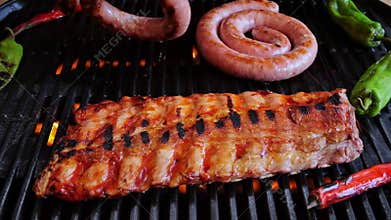 Chef turns over natural sausage on grill, twisted spiral. Cooking pork ribs on grill. Slow motion.