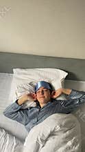 young woman in a sleeping mask rubs her eyes and stretches