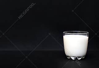 Milk glass on a side of isolated black background with copy space, healthy and natural drink concept backdrop