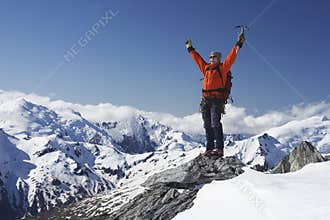 Mountain Climber With Arms Raised On Snowy Peak