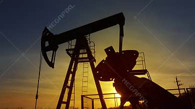 Working oil pump silhouette against sunset