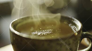 A closeup of a cup of steaming green tea highlighting its theutic properties and use in traditional medicine practices