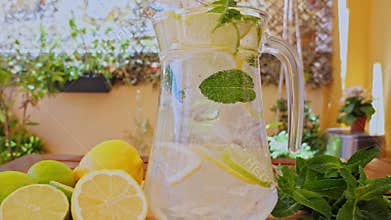 Soft Drink with Ice, Bubbles, Mint, lemon, lime in a glass decanter. Outdoors