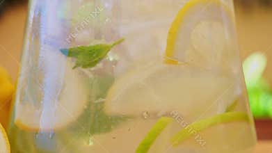 Drink with Ice, Mint, lemon, lime in a glass decanter. Outdoors. close up